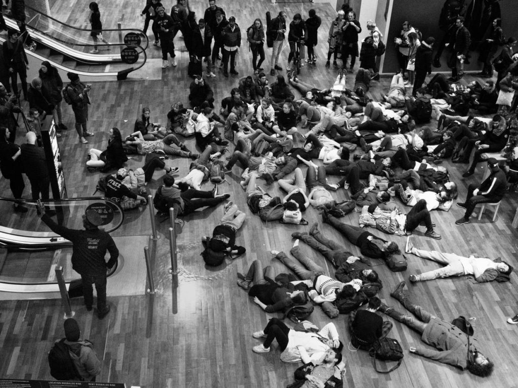 Une partie des manifestants improvise un sitting en plein milieu du centre commercial.